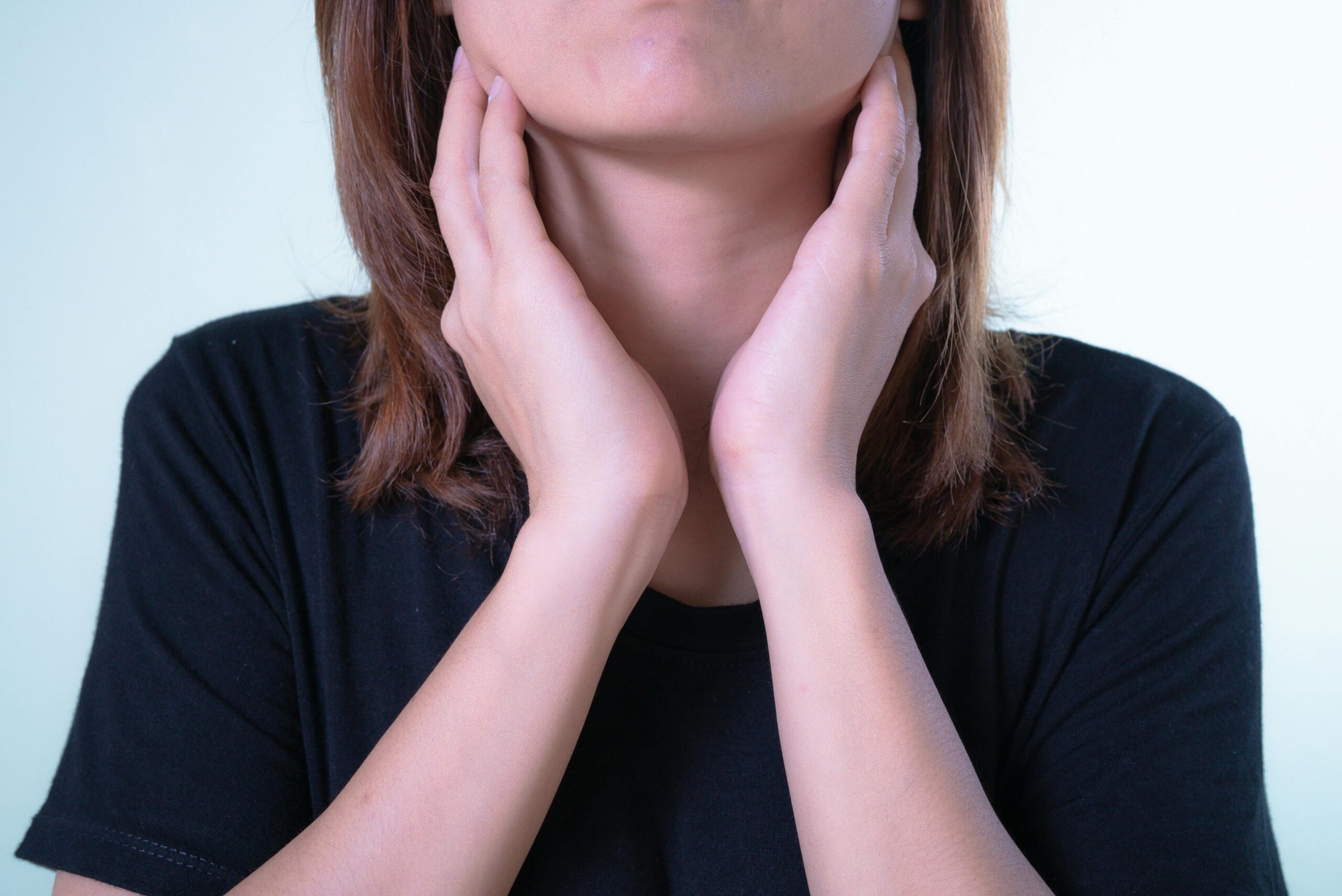 Thyroid_woman_bothered A woman touching her neck near her thyroids as if uncomfortable